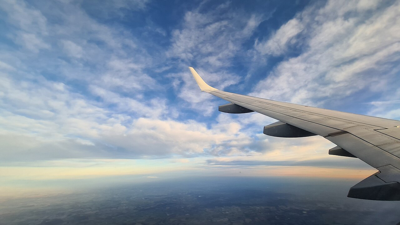 朝の青空と窓から見える飛行機の翼のイメージ写真